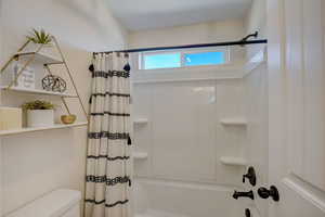 Bathroom with toilet and shower / tub combo with curtain