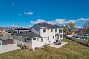 Back of house with a lawn, a mountain view, and a patio