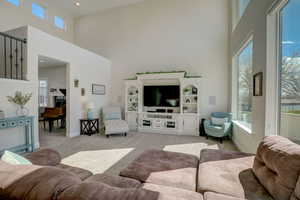 Living room featuring a wealth of natural light, light carpet, and a high ceiling