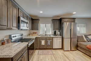 Kitchen with stainless steel appliances, light hardwood / wood-style flooring, a healthy amount of sunlight, and sink