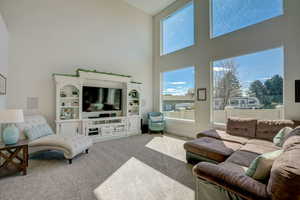 Carpeted living room featuring high vaulted ceiling