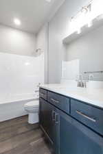 Full bathroom with vanity, toilet, wood-type flooring, and bathtub / shower combination