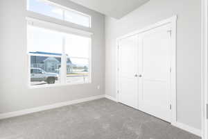 Unfurnished bedroom with multiple windows, carpet flooring, and a closet