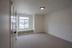 Empty room featuring a textured ceiling and light carpet