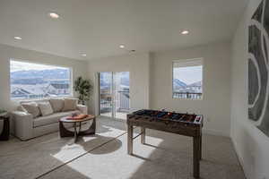 Recreation room featuring a wealth of natural light, a mountain view, and light carpet