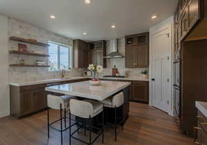 Kitchen featuring decorative backsplash, dark hardwood / wood-style flooring, a center island, and wall chimney exhaust hood