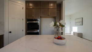 Kitchen with stainless steel double oven and light stone counters