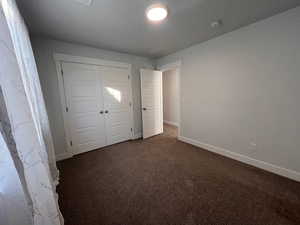 Unfurnished bedroom featuring a closet and dark colored carpet