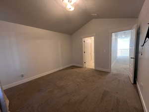 Interior space featuring vaulted ceiling, a textured ceiling, and carpet flooring