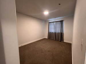 Unfurnished room featuring dark carpet