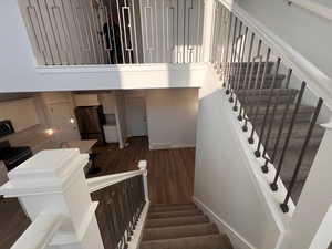 Stairs with a towering ceiling and hardwood / wood-style floors