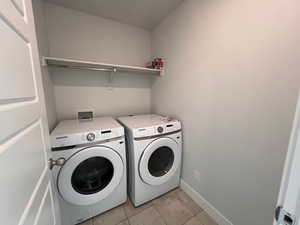 Laundry room with light tile patterned floors and washer and clothes dryer