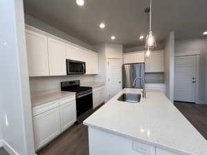 Kitchen featuring sink, white cabinetry, a center island with sink, pendant lighting, and stainless steel appliances