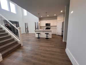 Kitchen with a breakfast bar, sink, white cabinetry, an island with sink, and stainless steel appliances