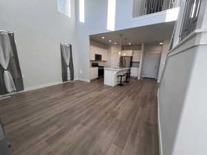 Unfurnished living room featuring dark hardwood / wood-style flooring, sink, and a towering ceiling