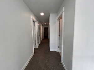 Corridor featuring dark carpet and a textured ceiling