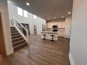 Kitchen with an island with sink, white cabinetry, a kitchen bar, hanging light fixtures, and stainless steel appliances