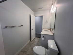 Bathroom with vanity, toilet, tile patterned flooring, and a textured ceiling