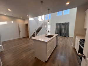 Kitchen with sink, white cabinetry, hanging light fixtures, a center island with sink, and stainless steel appliances