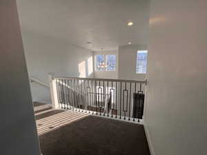 Hall with a textured ceiling, carpet floors, and a chandelier