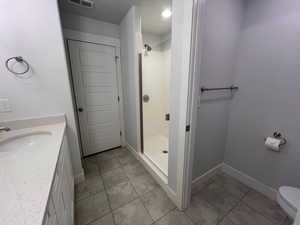 Bathroom featuring walk in shower, toilet, tile patterned flooring, and sink