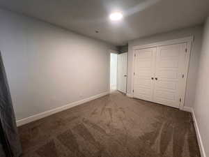 Unfurnished bedroom with dark colored carpet and a closet