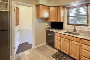 Kitchen with dishwasher, light hardwood / wood-style floors, sink, and stainless steel refrigerator