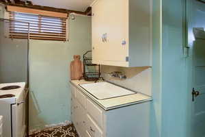 Kitchen with electric range, white cabinetry, and sink