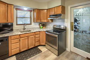 Kitchen featuring dishwasher, sink, backsplash, light hardwood / wood-style floors, and stainless steel range with electric cooktop