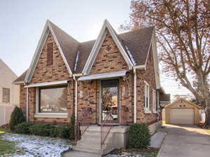 View of front of property featuring a front lawn, an outdoor structure, and a garage