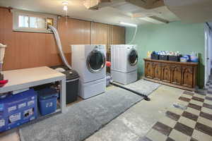 Washroom with wooden walls and washing machine and clothes dryer