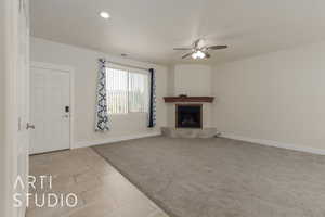 Unfurnished living room featuring ceiling fan and light colored carpet