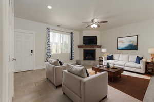 Living room featuring recessed lighting, a fireplace with raised hearth, visible vents, ceiling fan, and baseboards