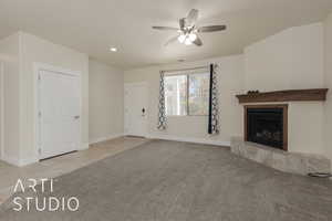 Unfurnished living room with light carpet, ceiling fan, and a tiled fireplace