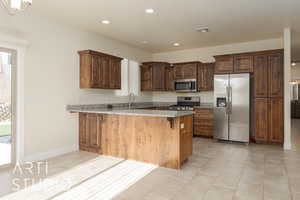 Kitchen with kitchen peninsula, light stone counters, stainless steel appliances, light tile patterned floors, and a breakfast bar area