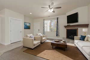 Living area with recessed lighting, light tile patterned flooring, a fireplace with raised hearth, and baseboards