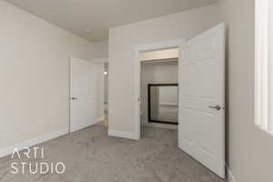 Unfurnished bedroom with a spacious closet, light carpet, and a closet