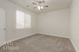 Spare room featuring ceiling fan, light colored carpet, and a wealth of natural light