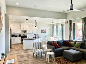 Living room with ceiling fan, sink, light hardwood / wood-style floors, and a textured ceiling