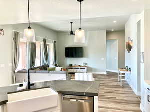 Kitchen featuring white cabinetry, dishwasher, sink, hanging light fixtures, and light hardwood / wood-style floors