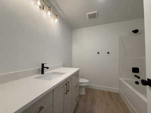 Full bathroom featuring vanity, wood-type flooring, a textured ceiling, toilet, and shower / bathing tub combination