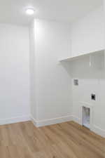 Laundry area with hookup for an electric dryer, hookup for a washing machine, and light hardwood / wood-style floors