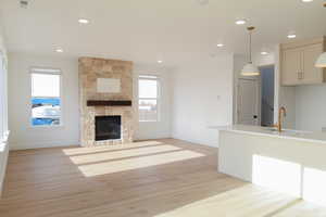 Unfurnished living room with a stone fireplace, sink, and light hardwood / wood-style flooring