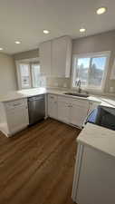 Kitchen with white cabinetry, dishwasher, sink, and plenty of natural light