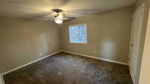 Empty room with ceiling fan, dark carpet, and a textured ceiling