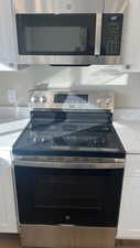 Interior details with white cabinets, light stone countertops, and appliances with stainless steel finishes