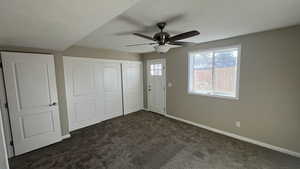 Unfurnished bedroom with dark colored carpet, ceiling fan, and a closet