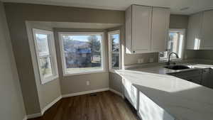 Kitchen featuring white cabinets, light stone countertops, sink, and light hardwood / wood-style flooring