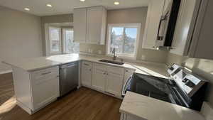 Kitchen featuring white cabinets, a healthy amount of sunlight, kitchen peninsula, and appliances with stainless steel finishes