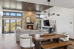 Living room featuring a fireplace, high vaulted ceiling, a healthy amount of sunlight, and wood-type flooring